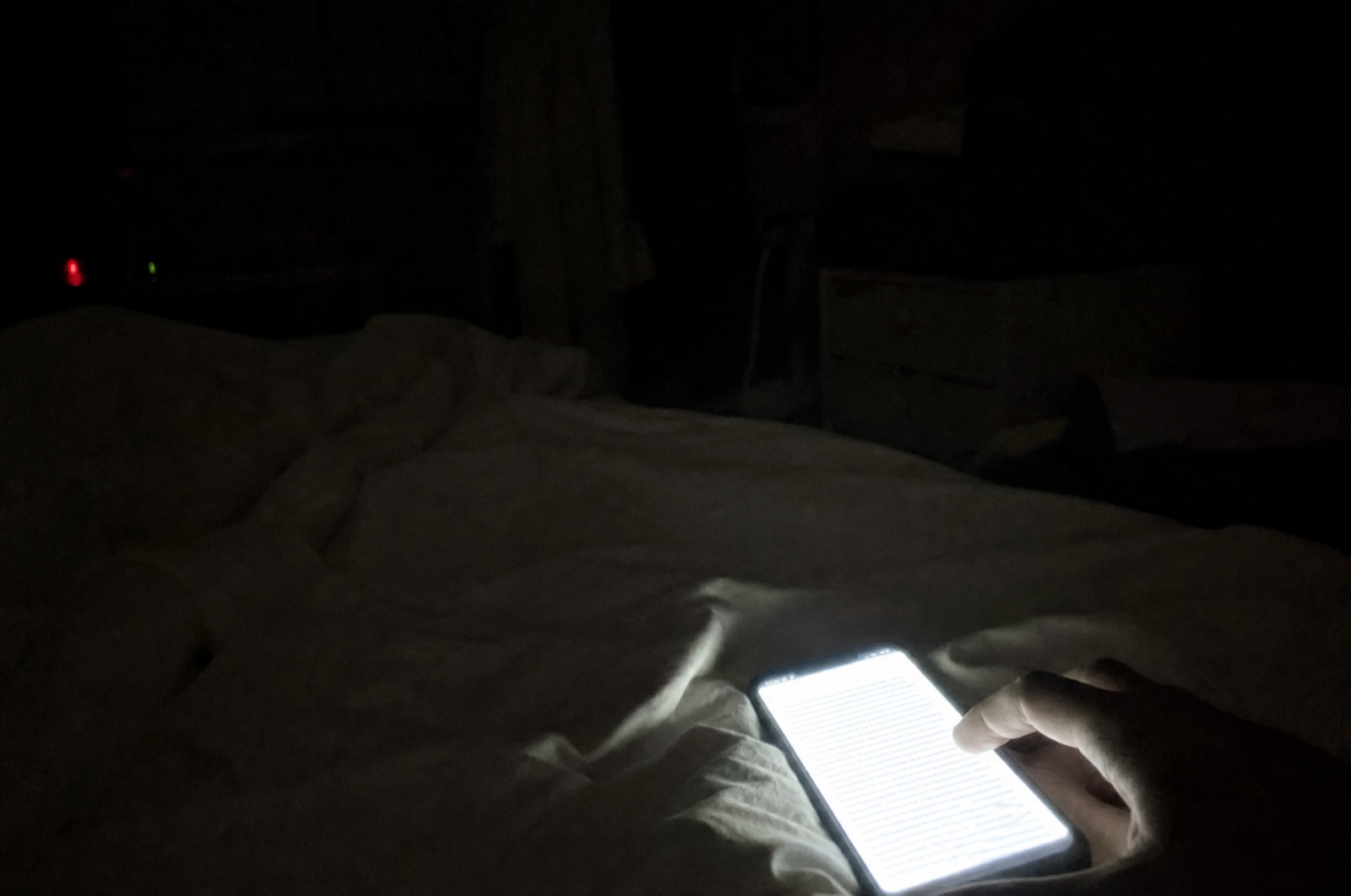 A phone screen glowing in a dark bedroom, showing a wall of text