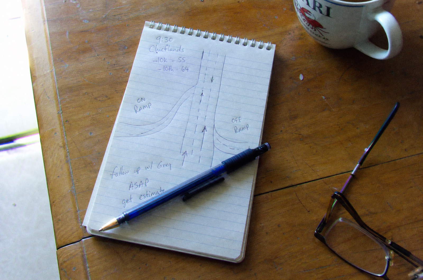 A handwritten notepad drawing of a road with an on ramp and an off ramp on a kitchen table