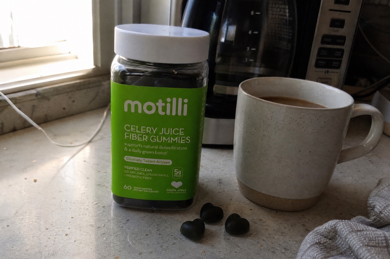 Motilli Celery Juice Fiber Gummies jar on a kitchen counter beside morning coffee
